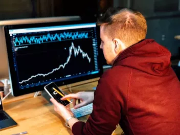 a bad stock photo of someone pretending to analyse stocks on a computer